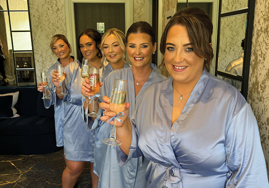 Bridesmaids in blue robes holding champagne flutes